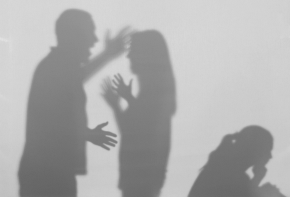 Shadows of people standing in front of one another gesturing as if they are in a heated argument.